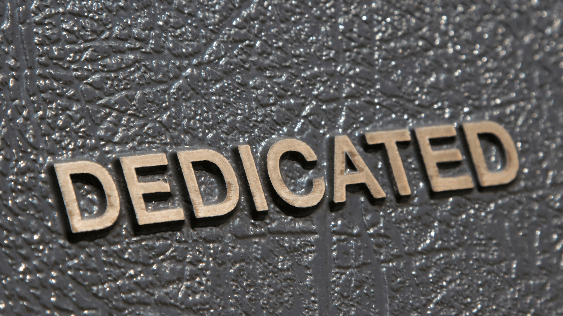 The background looks like leather - a deep brown leather with the word "dedicated" on it.